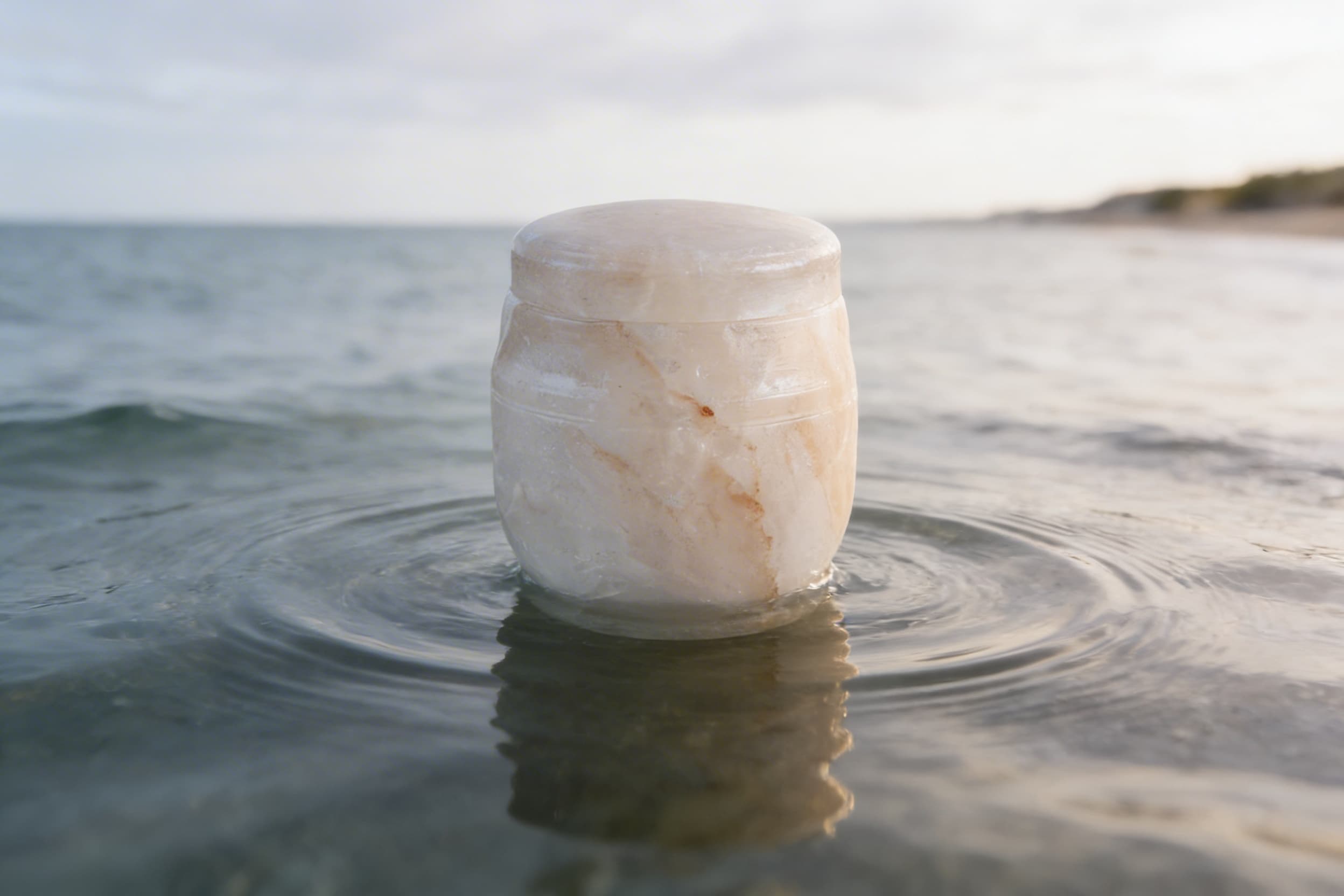 A biodegradable water urn floating briefly on calm ocean water during a memorial ceremony