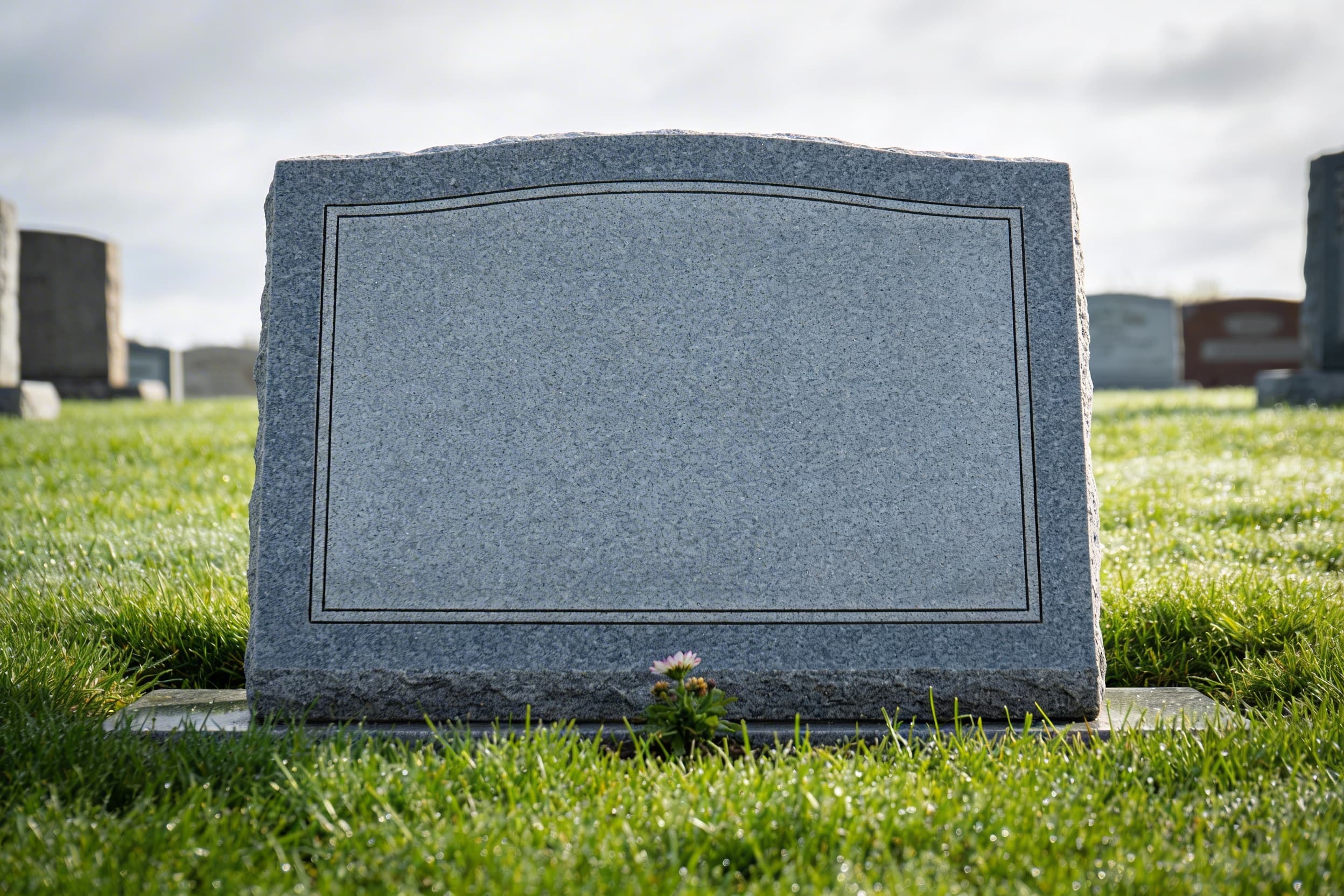 A polished gray granite flat grave marker set flush with green grass in a well-maintained cemetery