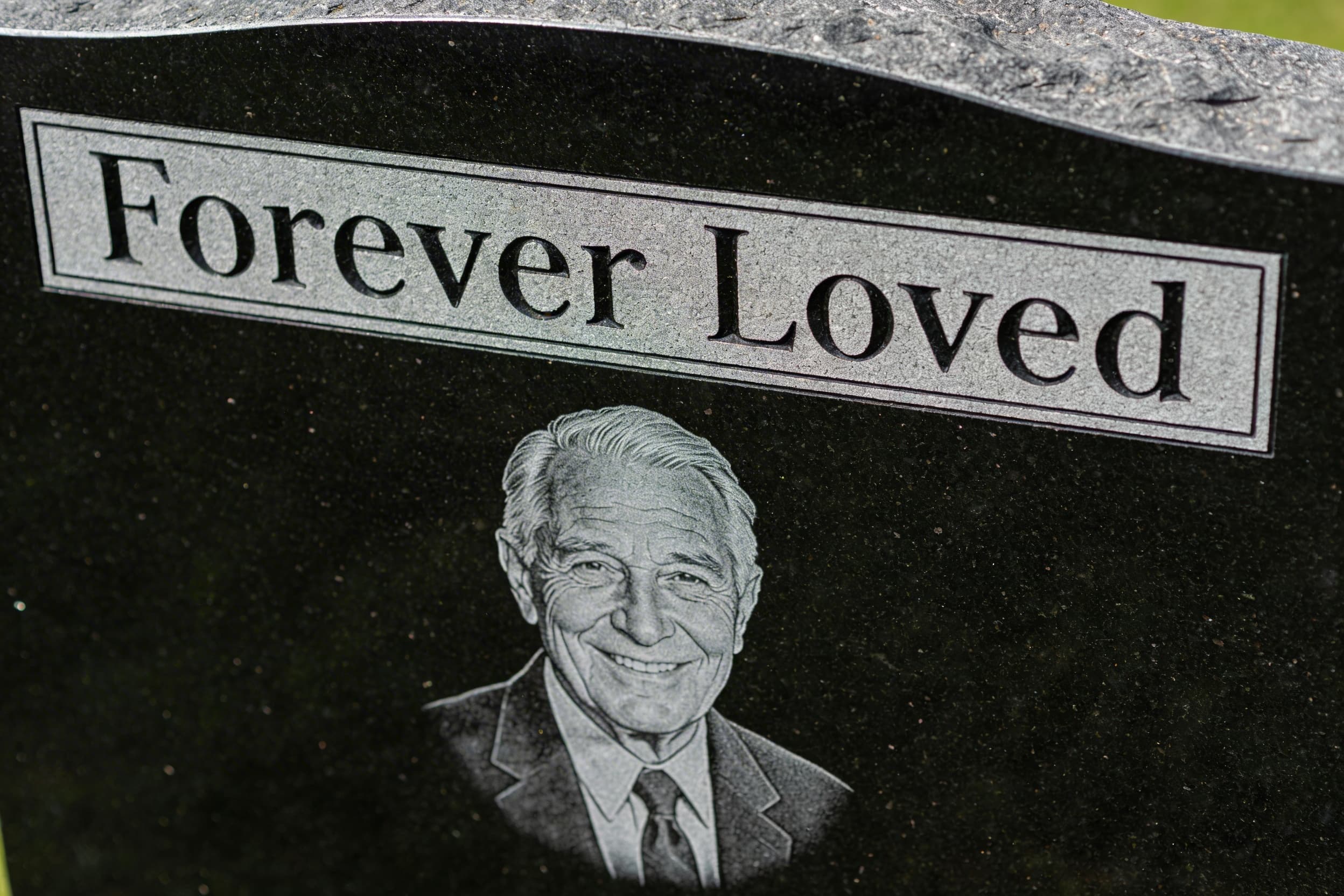 A detailed laser-etched portrait of an elderly man on a polished black granite headstone with sandblasted lettering above showing the name and dates