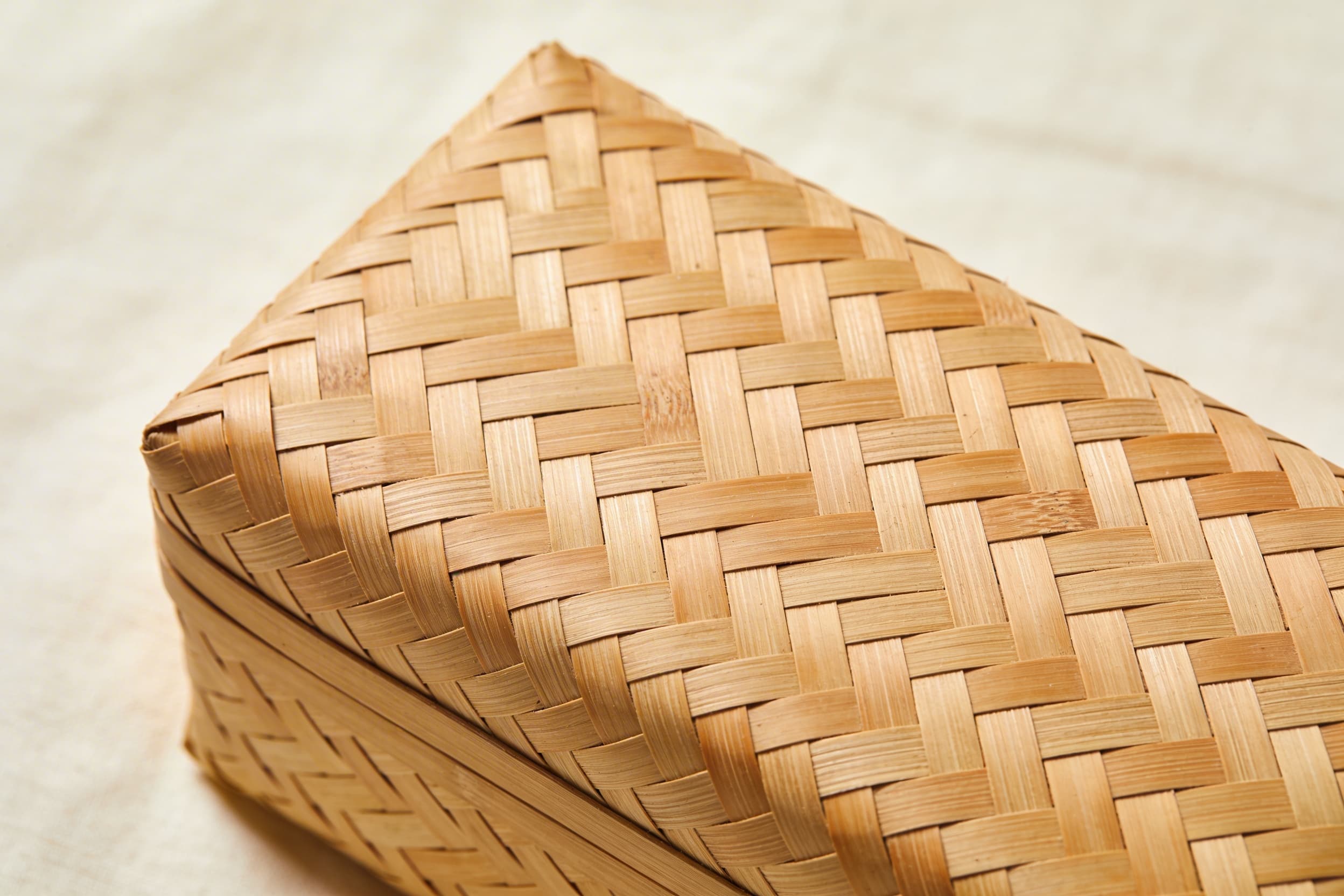 Close-up detail of a handwoven bamboo casket showing the tight natural weave pattern and warm tan coloring