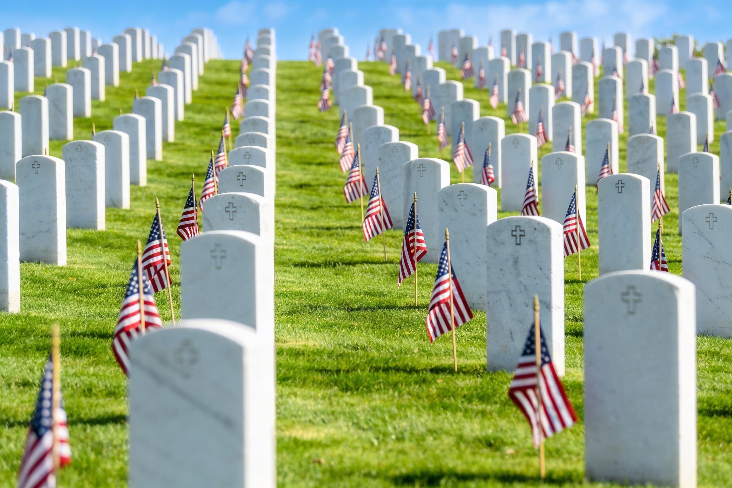 Veterans cemetery with upright headstones and american flags.