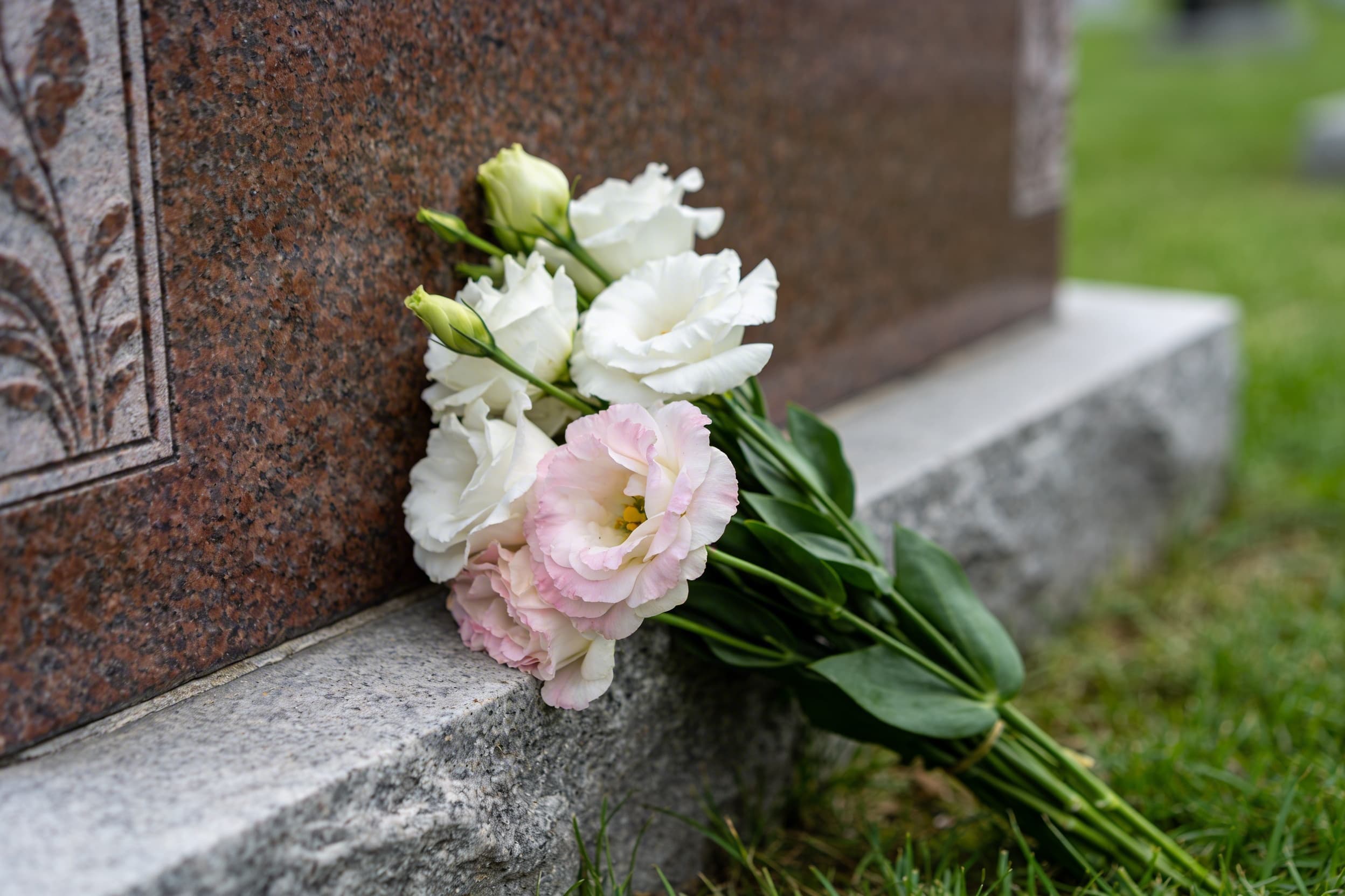 Flowers resting up against an upright headstone