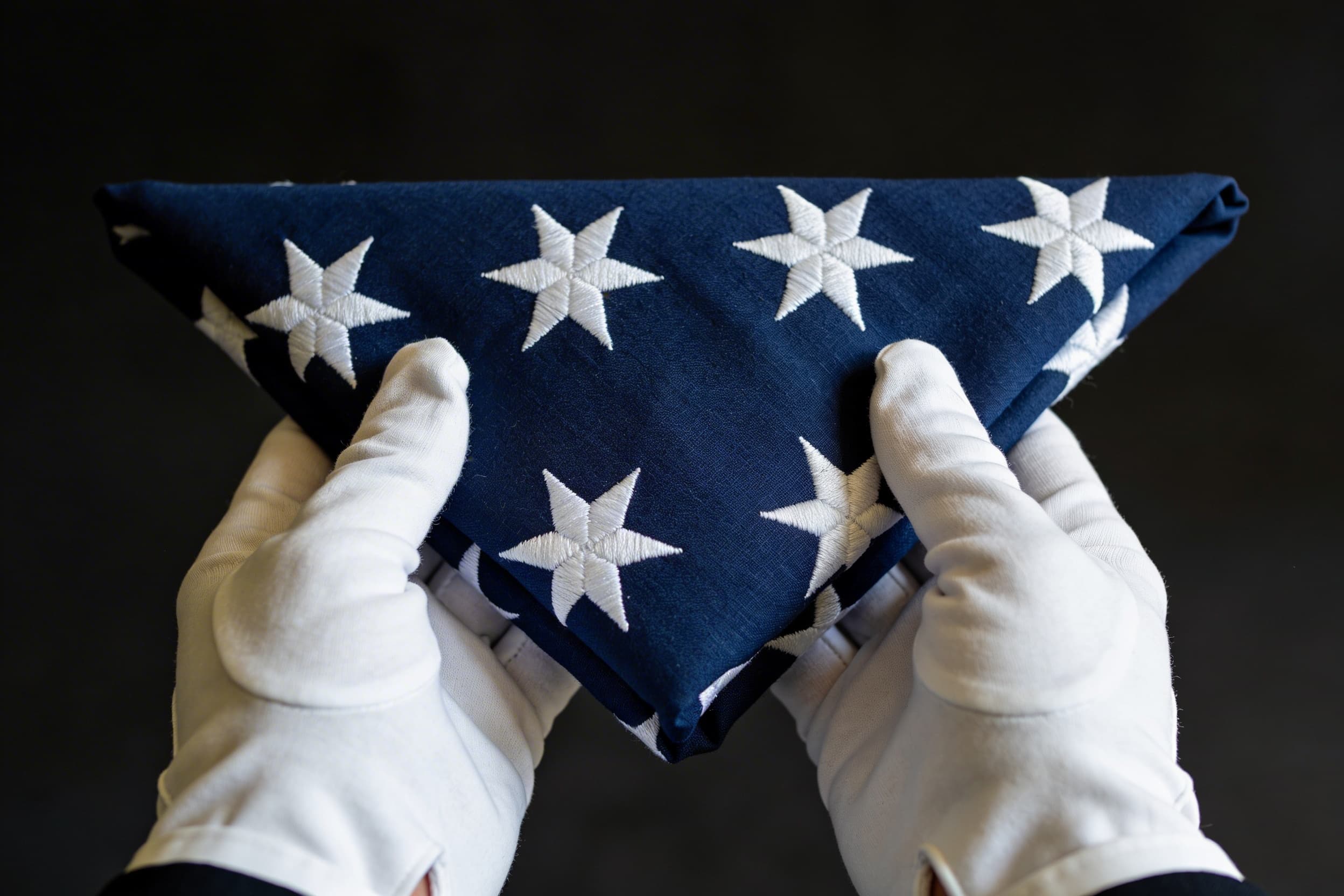A neatly folded triangular American flag being presented to a family member at a military funeral ceremony