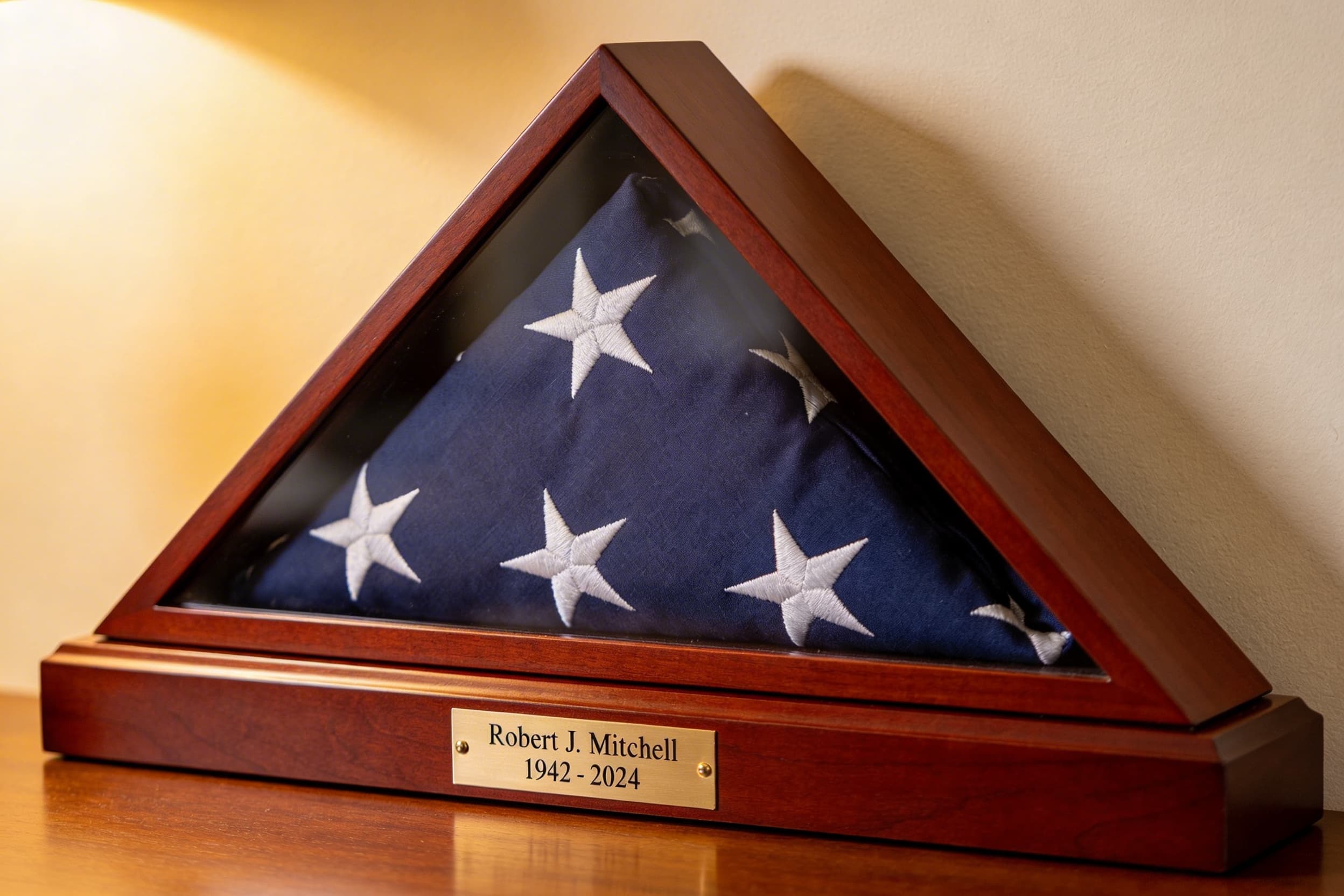 A tightly folded American flag displayed in a cherry wood triangle flag display case mounted on a wall