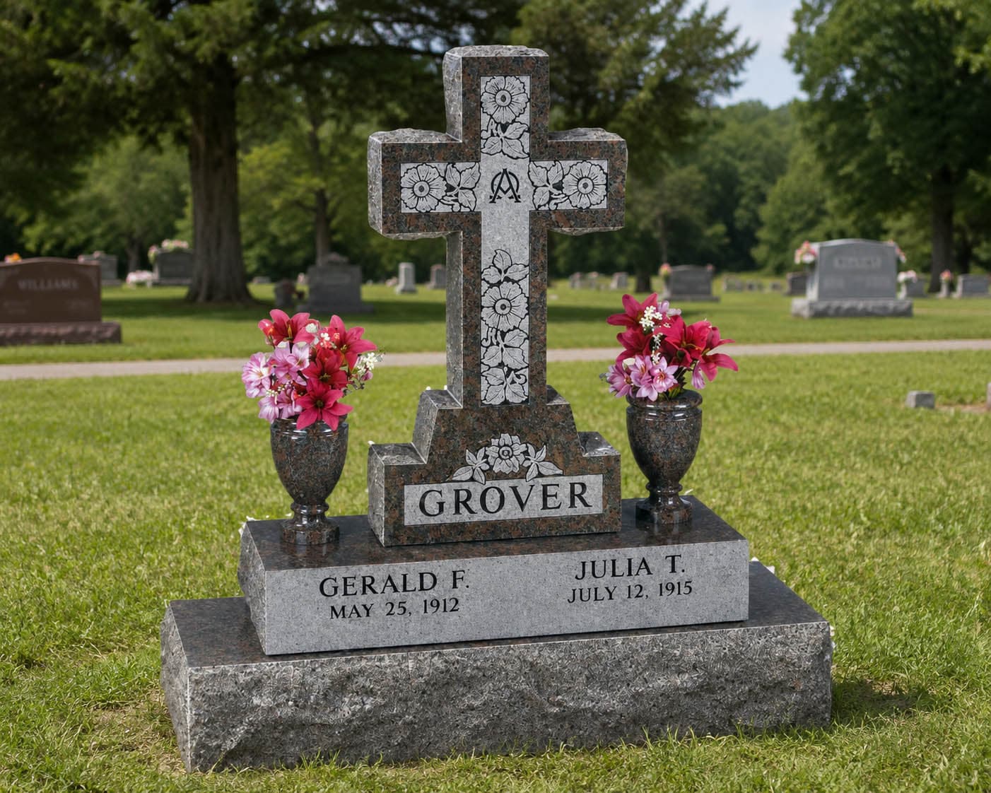 An upright cross headstone sitting in the cemetery grass with flowers.