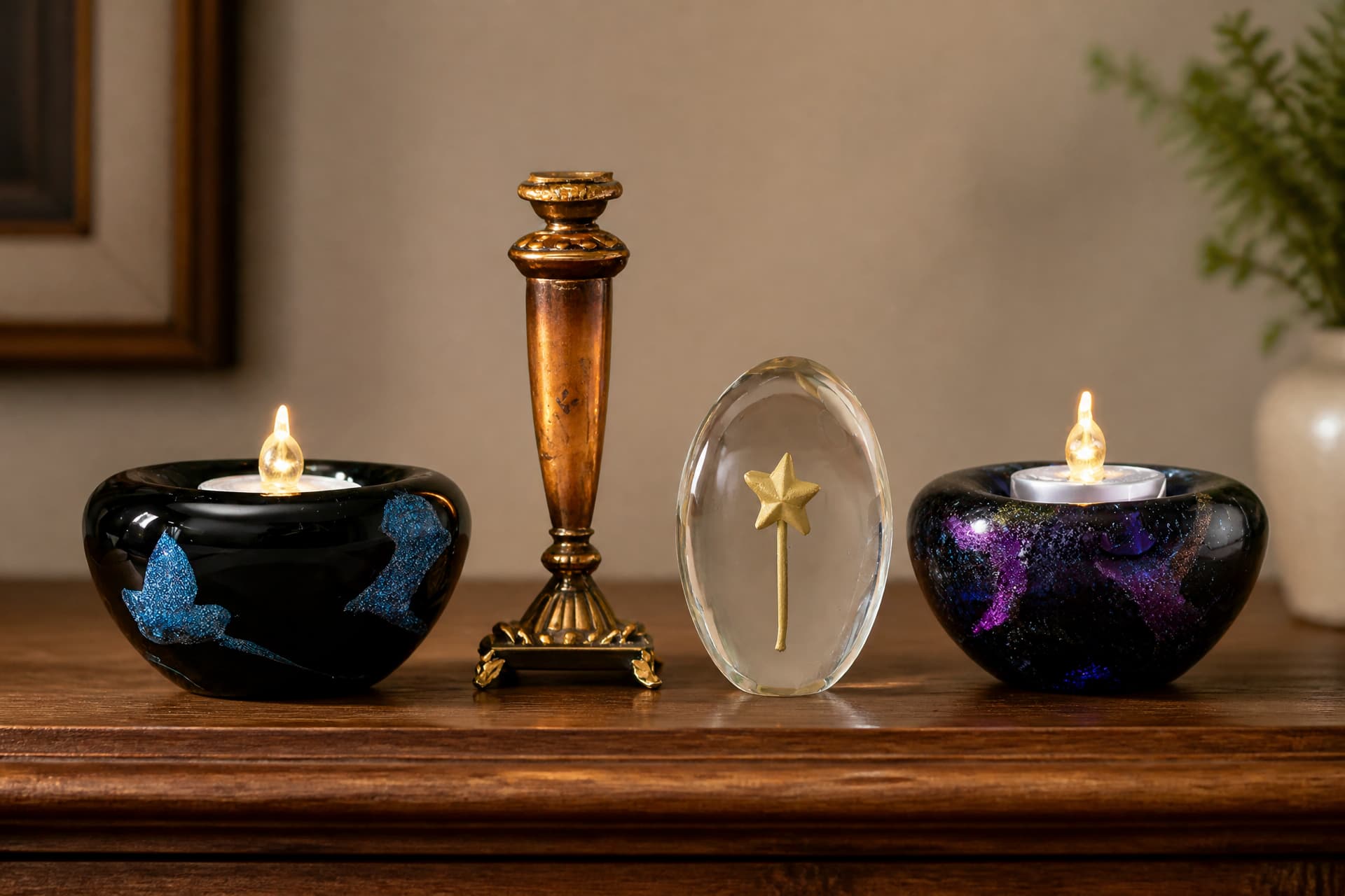 A black glass tealight holder flecked with blue, a bronze pillar candle holder, a clear glass oval set with a small gold star, and a black glass tealight holder flecked with purple