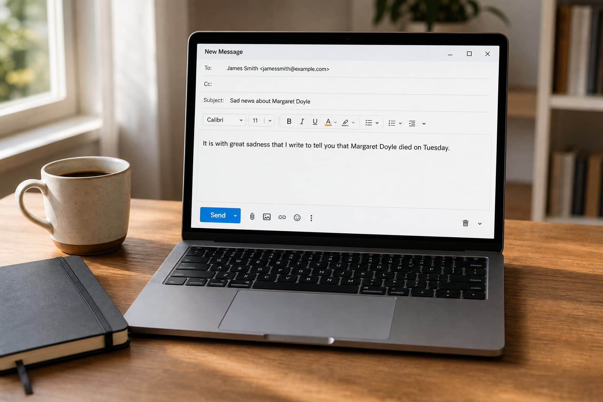 An open laptop showing an email compose window with the subject line "Sad news about Margaret Doyle", a cup of coffee and a closed notebook beside it