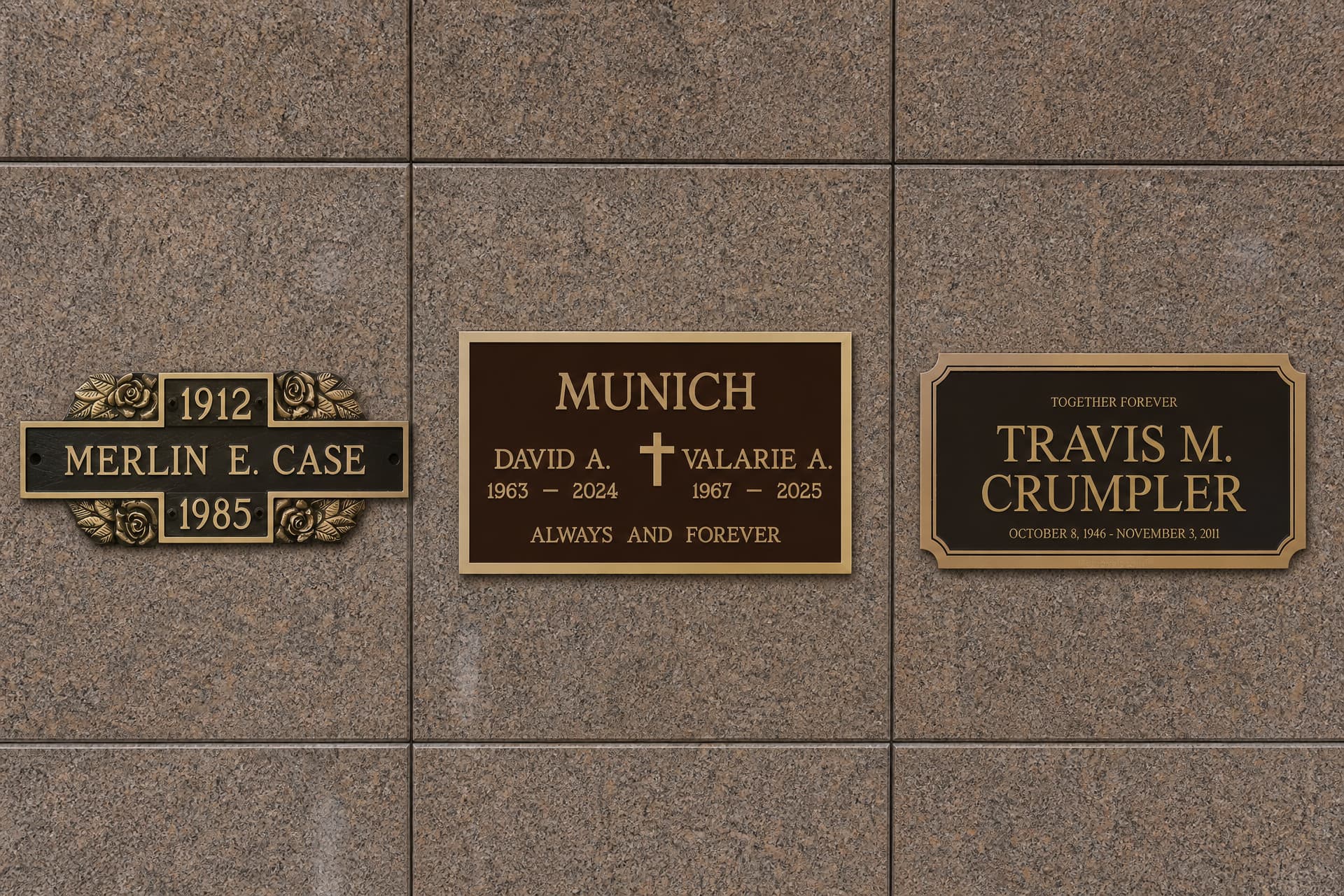 Three cast bronze niche plaques mounted upright on a polished granite crypt wall, each with a name and dates