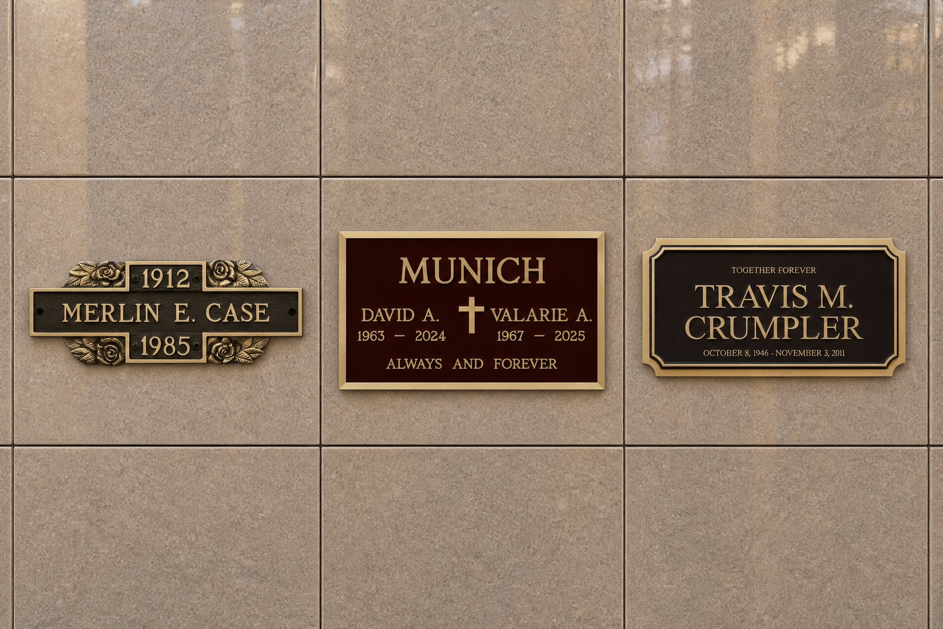 Three cast bronze niche plaques mounted upright on a polished granite crypt wall, each with a name and dates