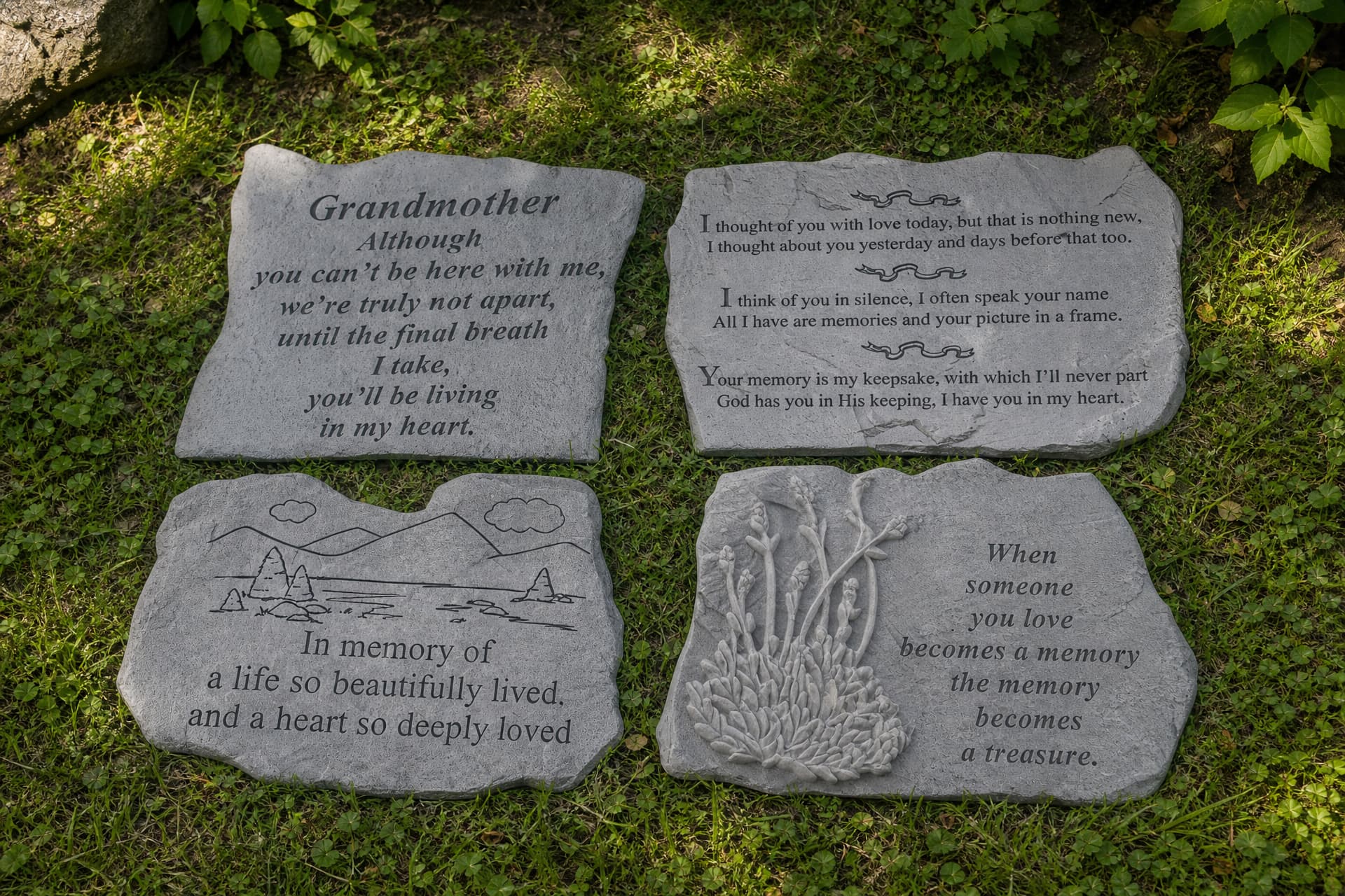 Four engraved memorial garden stones arranged on grass among low planting, each carrying a different verse or dedication