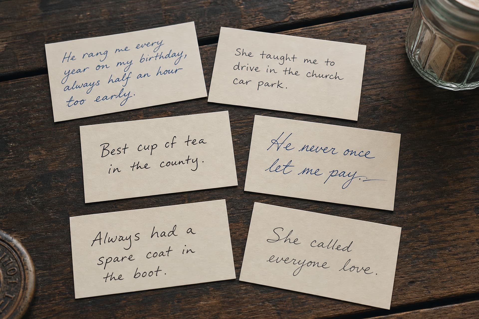 A handful of handwritten memory cards spread on a table beside a glass jar, each carrying a short line in different handwriting