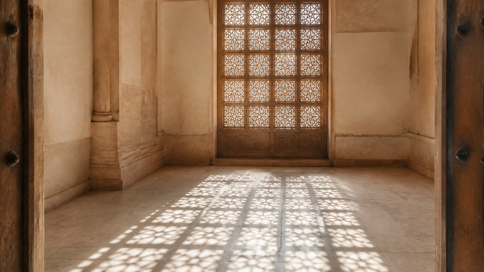 Daylight falling through a carved wooden screen onto a bare stone floor in an empty room, casting a lattice of geometric shadows