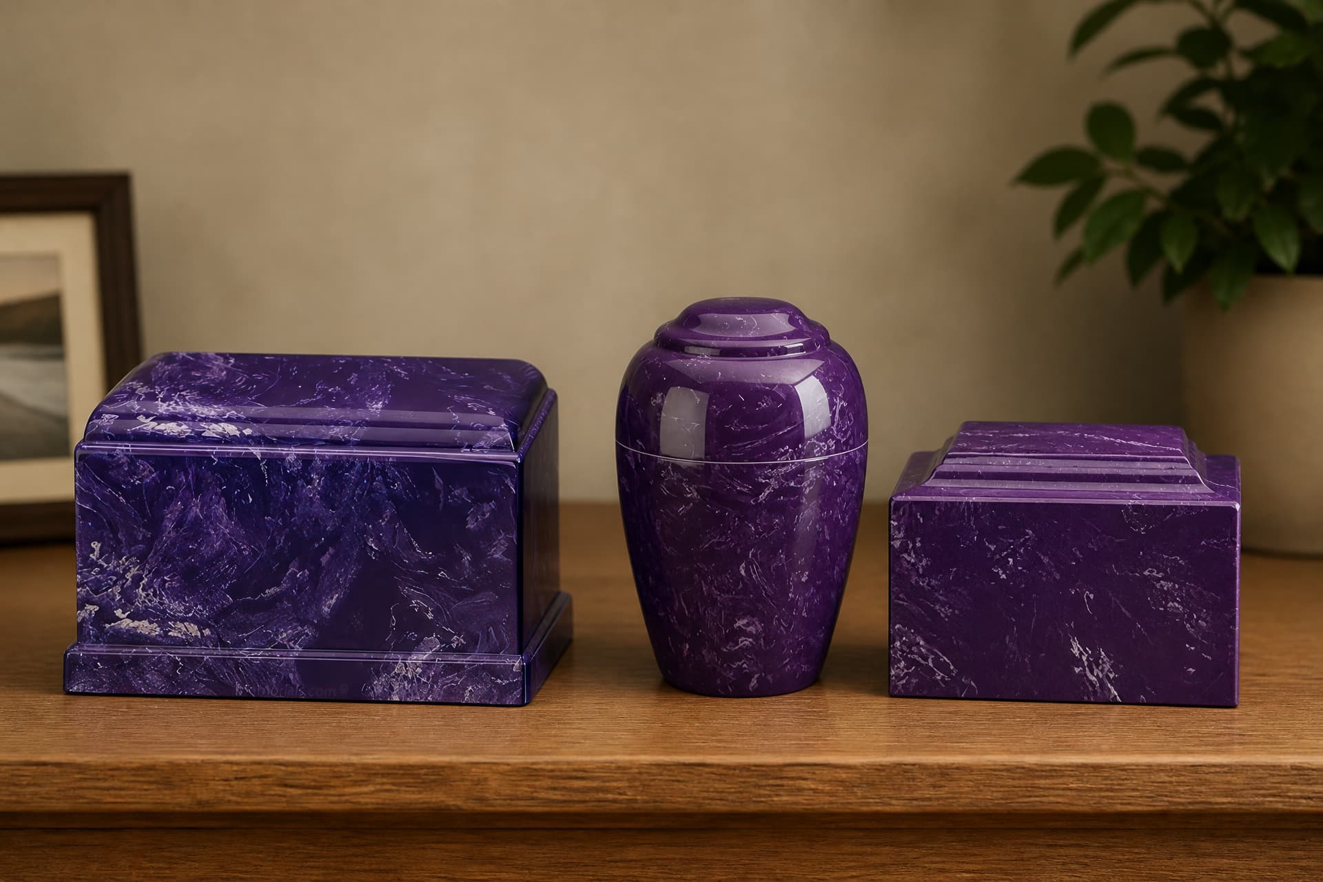 A rectangular purple marbled cultured stone urn, a purple vase-shaped urn and a smaller purple box urn standing left to right on a wooden shelf in warm light, a framed picture blurred behind