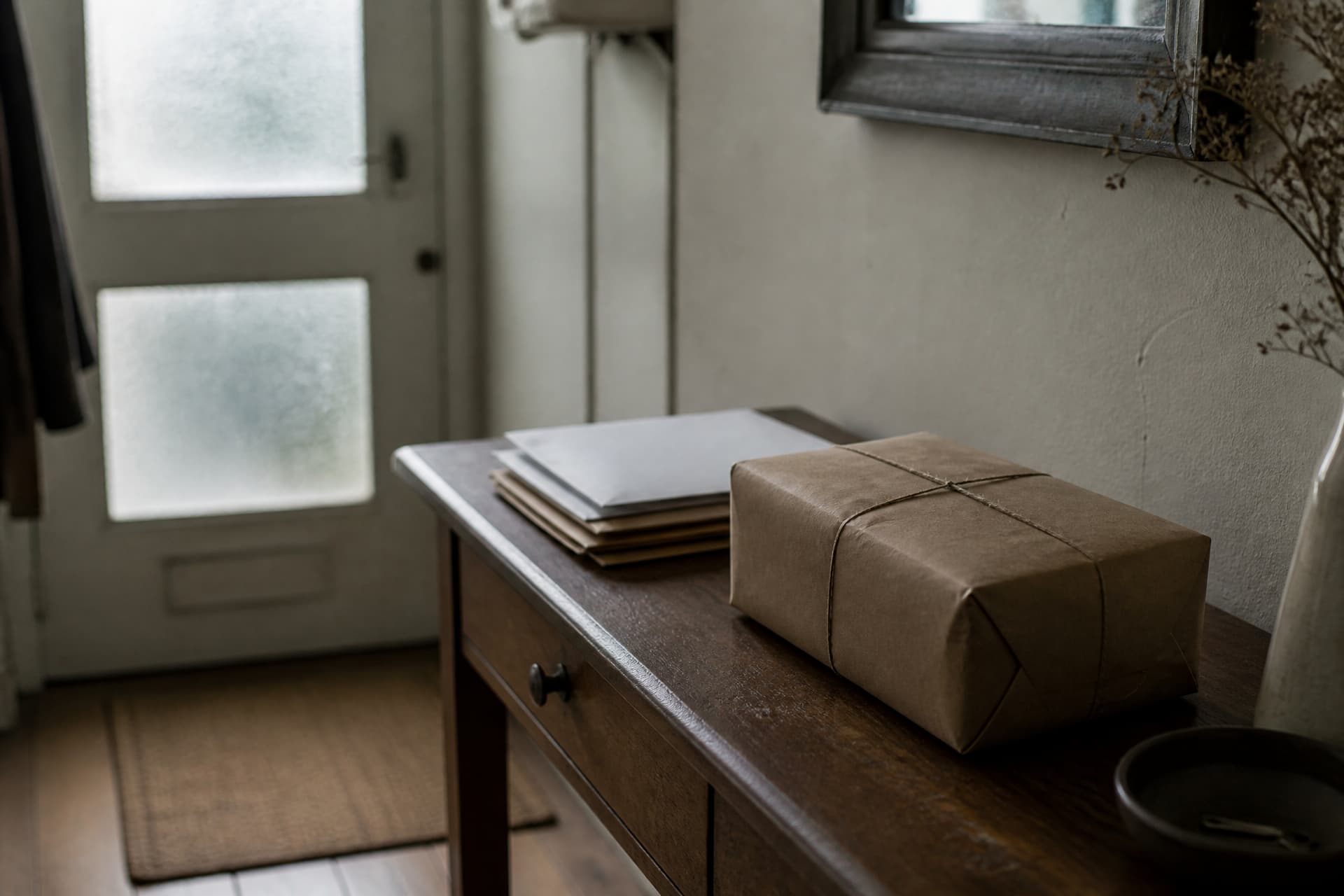 An unopened package on a hall table beside unopened mail