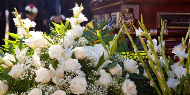 Funeral flower arrangement next to a casket